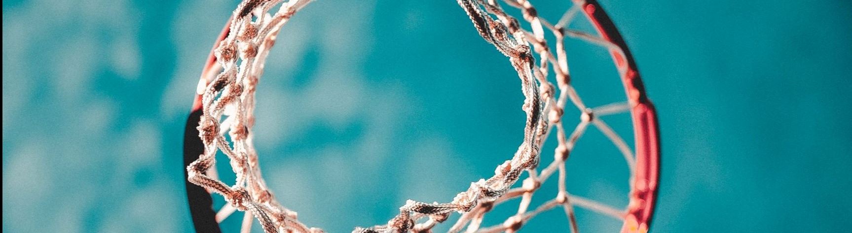 upward photo of basketball hoop and blue, cloudy sky