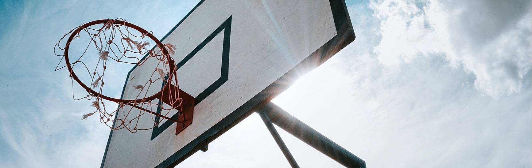 Upward photo of basketball hoop with sun behind backboard